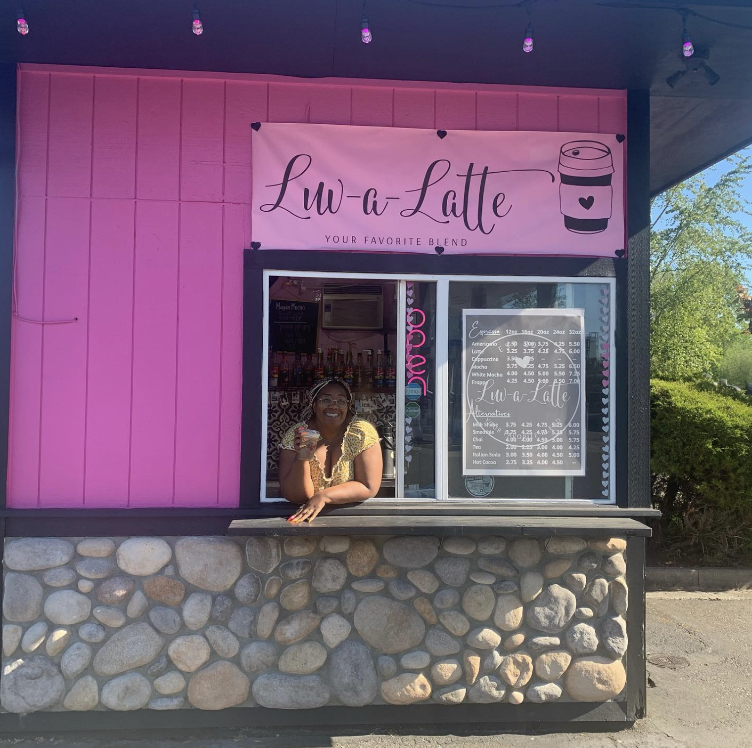 Luv-a-Latte drive-thru coffee shop exterior painted bright pink with the owner leaning out the window